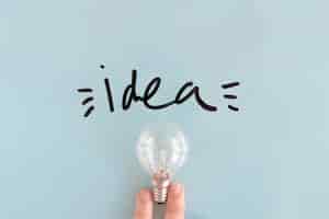 Бесплатное фото Крупным планом рука человека, держащей лампочку возле черного слова идеи