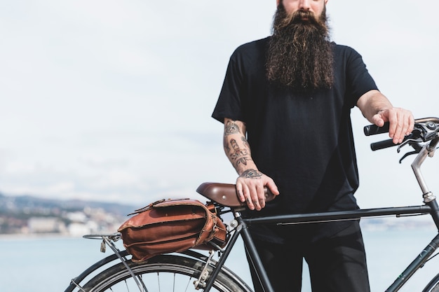Бесплатное фото Крупный план бородатого молодого человека, стоящего на велосипеде