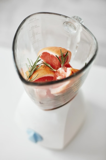 Бесплатное фото Закройте вверх частей грейпфрута и розмаринового масла в blender. здоровый фитнес, диетическое питание.