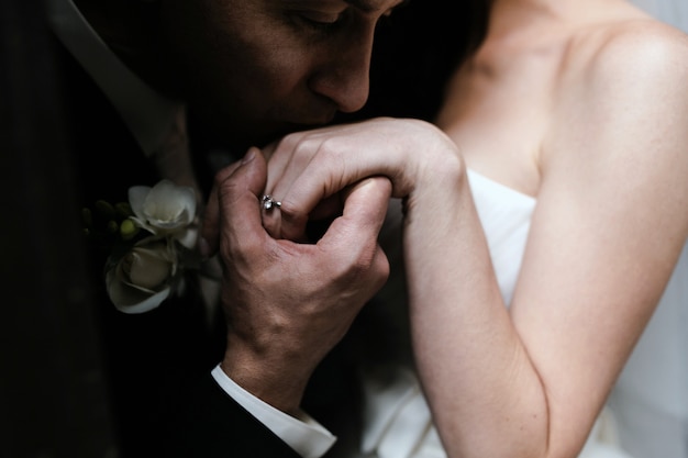 무료 사진 그의 아내의 손을 키스하는 신랑의 클로즈업