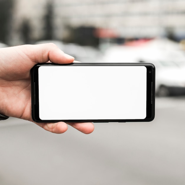Бесплатное фото Крупным планом руки, держащей мобильный телефон, показывая пустой белый экран