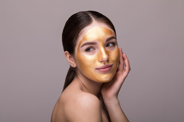 Бесплатное фото Крупным планом здоровой молодой женщины с золотой косметической маски на мягкой коже.