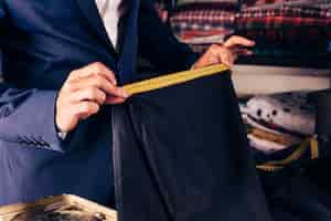 Бесплатное фото Крупный план мужской дизайнер моды, принимая измерения голубой ткани с желтой измерительной ленты