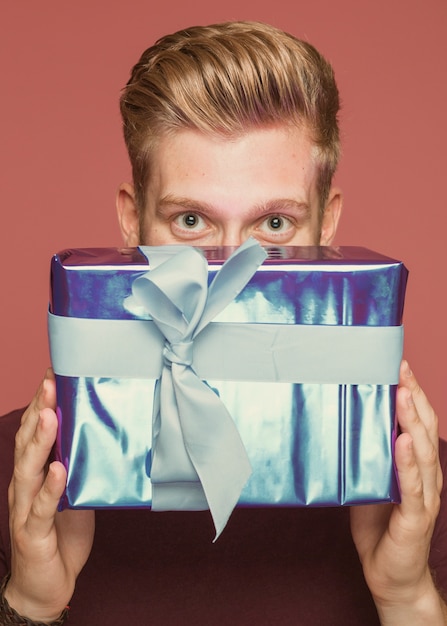 Бесплатное фото Крупный план мужчина держит обернутую подарочную коробку под глаза