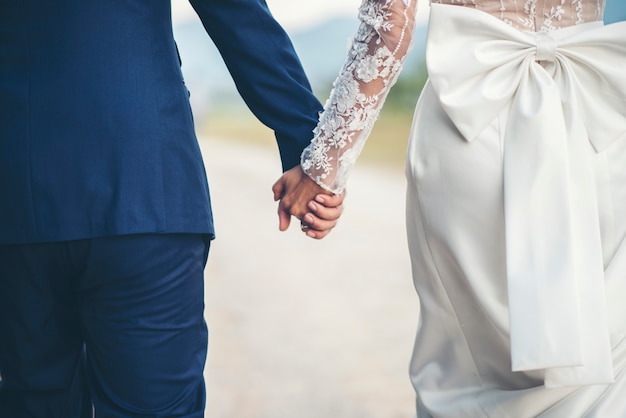 結婚式​の​日に​手​を​繋いでいる​夫婦​の​クローズアップ