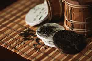 Бесплатное фото Закройте чай puer с золотой жабой на бамбуковой циновке. черный фон.