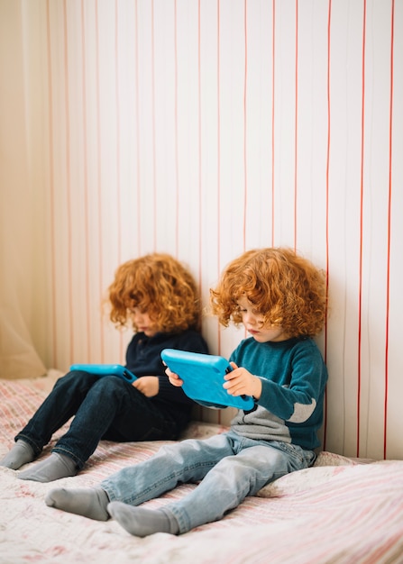 Бесплатное фото Крупный план близнецов с рыжими волосами, глядя на цифровой планшет