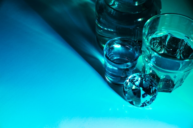 Крупным планом стаканов воды и бутылка с бриллиантом на синем фоне ярко