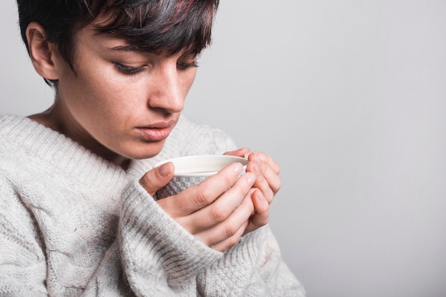 無料写真 灰色の背景にコーヒーを飲む女性のクローズアップ