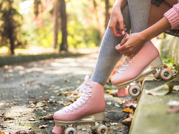 Бесплатное фото Конец-вверх женщины связывая шнурок на коньках ролика в носках