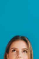 Бесплатное фото Крупным планом лицо молодой женщины, глядя на синем фоне