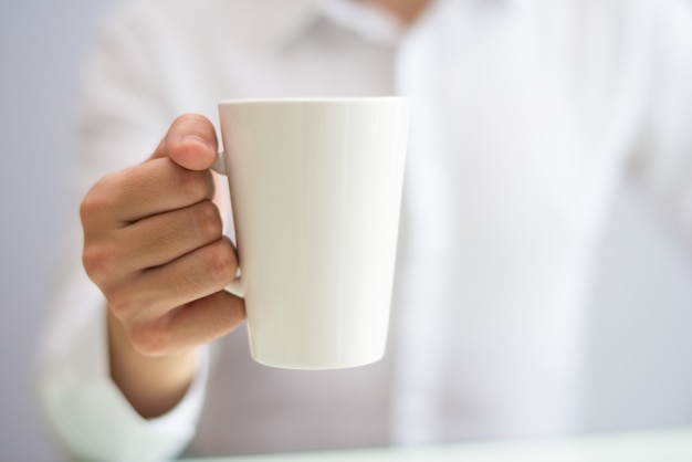 Close-up of office employee drinking coffee from mug