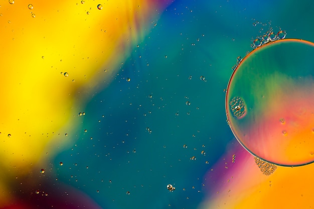 Close-up oily bubbles and droplets in colourful watery backdrop