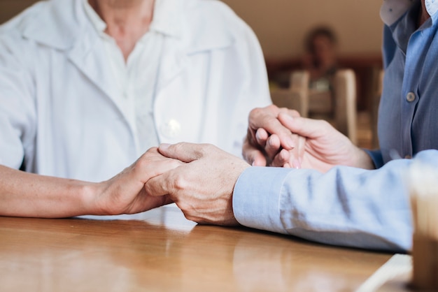 Close-up old people holding hands