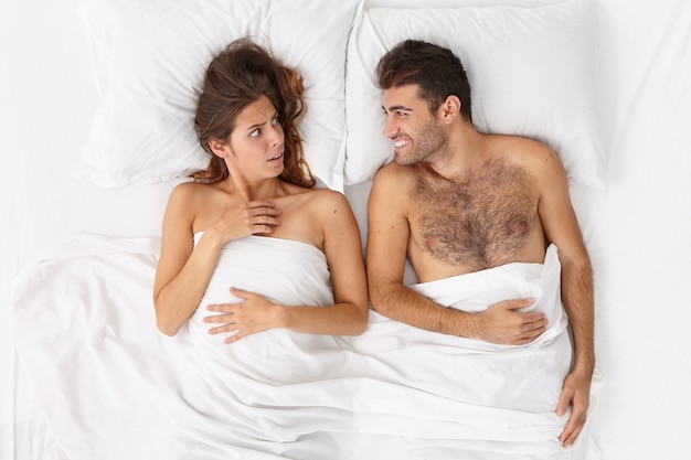 Бесплатное фото Крупным планом пара, лежа в постели под белым одеялом