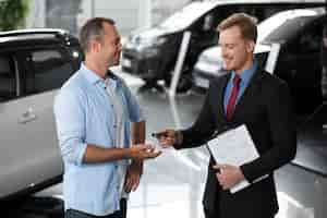 Бесплатное фото Крупным планом на клиента с деловым человеком в автосалоне