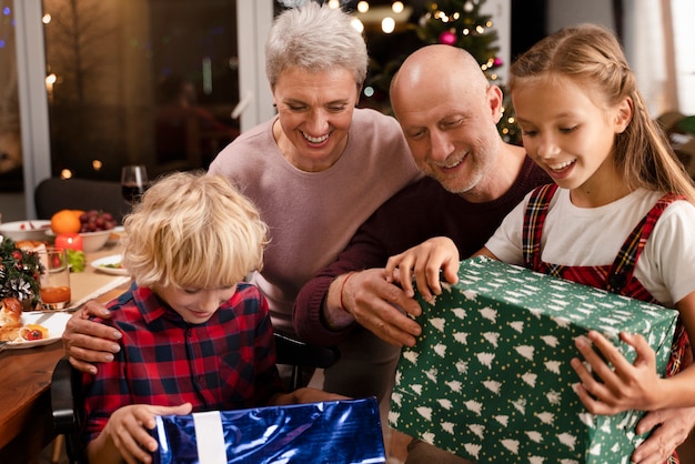 Крупным планом бабушки и дедушки и дети открывают подарки