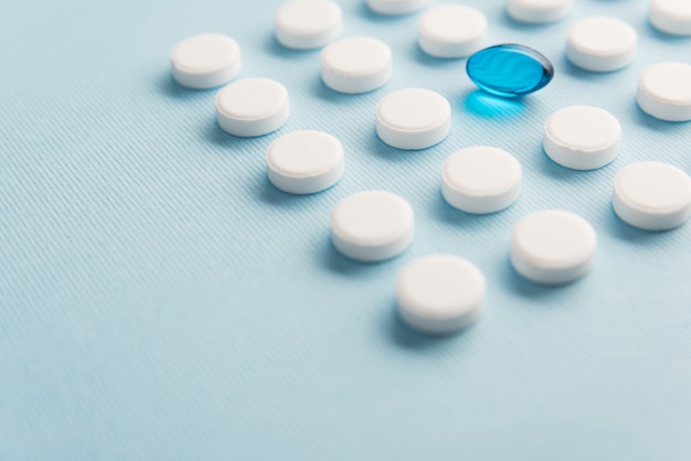 Close up of one capsule surrounded by white tablets