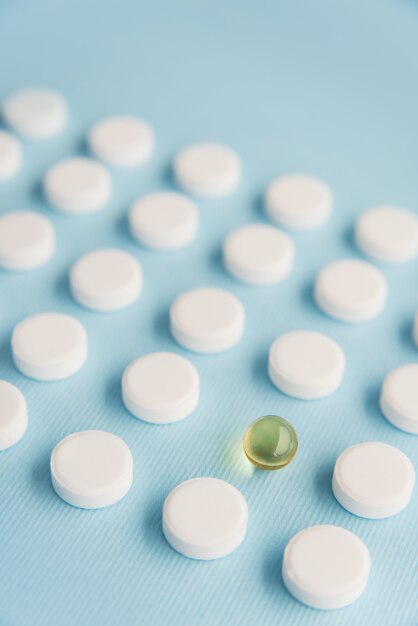 Free photo close up of one capsule surrounded by white tablets