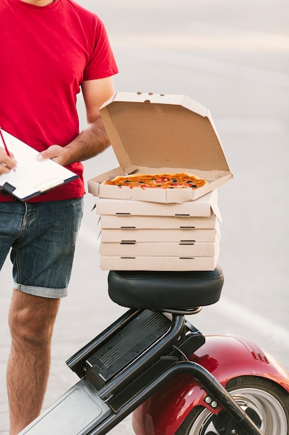 Foto gratuita scatola per pizza aperta primo piano sulla motocicletta