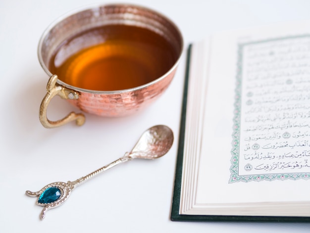 Close up opened quran with tea cup