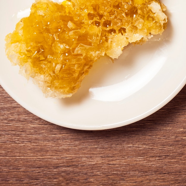 Close-up of organic natural honeycomb in plate over wooden table