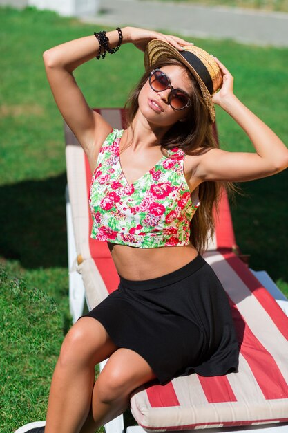 Close up outdoor portrait of young woman smiling , sitting on green fresh grass in sunny spring park