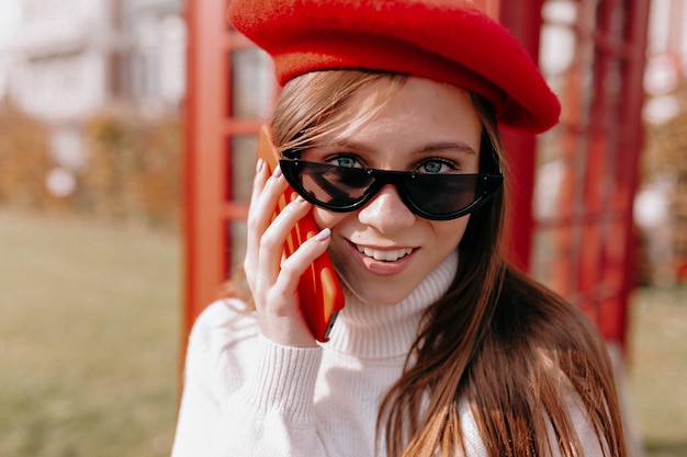 Primo piano esterno ritratto di efficace ed elegante donna moderna che indossa il berretto rosso