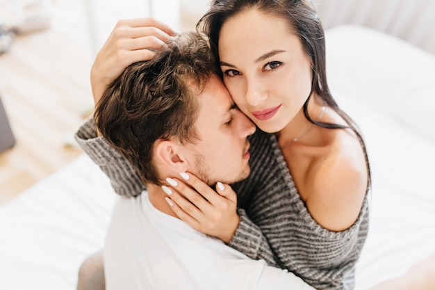 Close-up overhead photo of charming female model hugging with boyfriend in morning