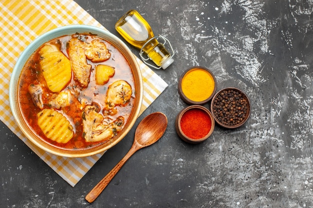 Close up overhead view of various spices soup with chicken and fallen oil on dark