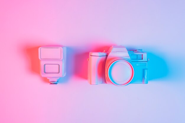 Close-up of painted lens with vintage camera against pink background