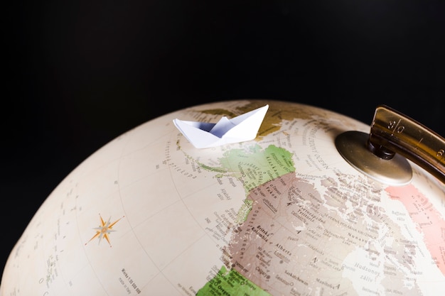 Free photo close-up of paperboat over globe