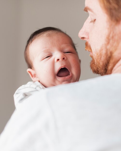 Close-up parent holding yawning baby