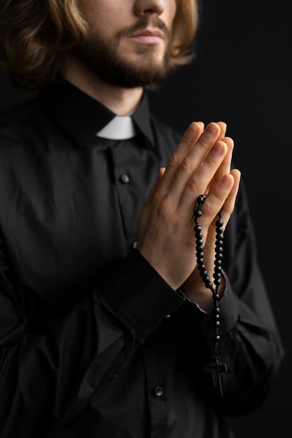 ロザリオで祈っている牧師をクローズアップ