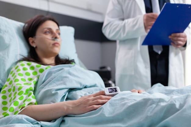 Close up patient lying in bed with finger heart rate monitor pulse