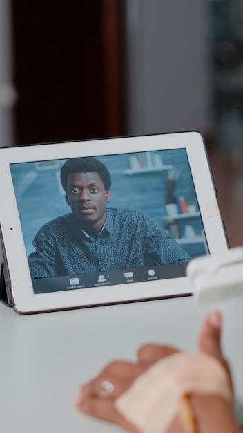 Free photo close up of patient using video call on digital tablet to talk to man while laying in hospital ward bed. person talking to friend on online video conference on device. remote communication