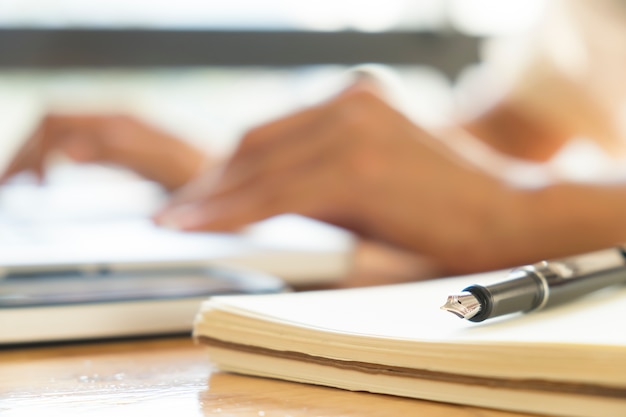 Close up pen and blur bokeh working hands of asian businesswoman