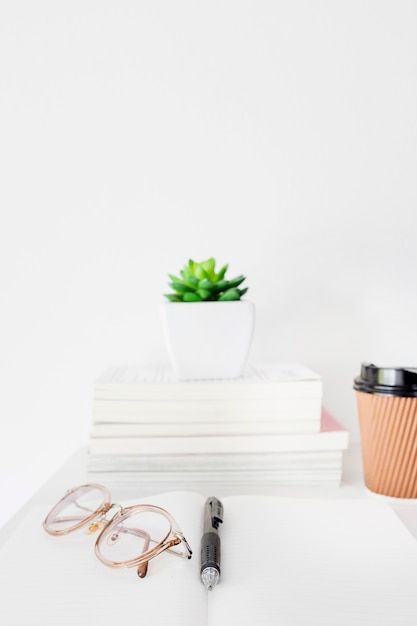 Free photo close-up of pen and spectacles on open notebook over desk