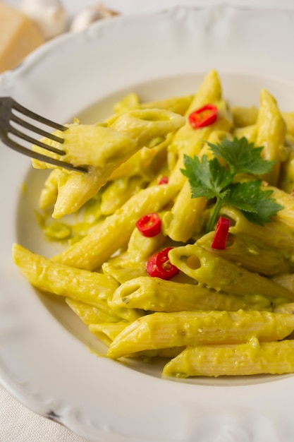 Close up penne with pesto and red peppers in bowl