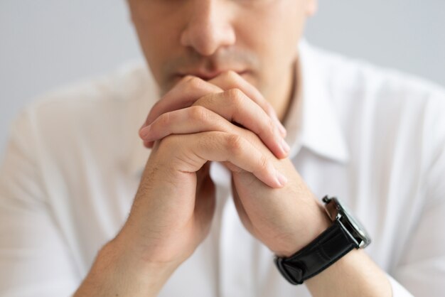 Close-up of pensive young businessman sitting with clasped hands