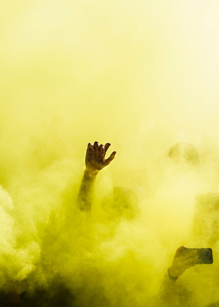 Close-up of people dancing and in yellow explosion of holi color