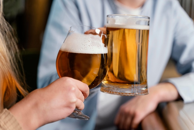 Close-up people holding beer mugs