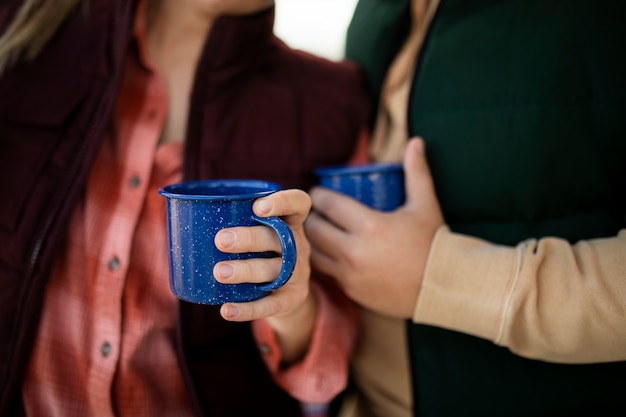 Free photo close up people holding blue mugs