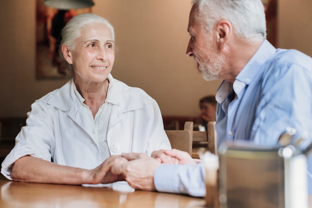 Close-up people holding hands at restaurant