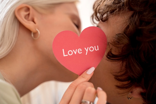 Foto gratuita chiuda in su persone che si baciano dietro il cuore rosa