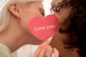 Free photo close up people kissing behing pink heart