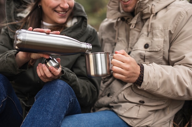 Close-up persone con thermos e tazza