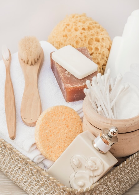 Close-up of perfume bottle; brush; sponge; soap; cotton swab; towel and body scrub in tray