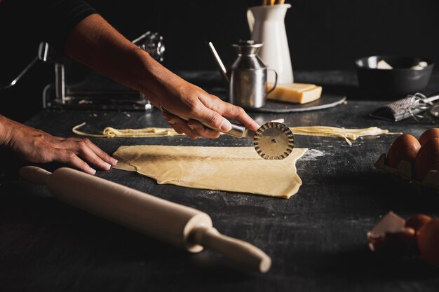 Close-up person cutting dough for pasta