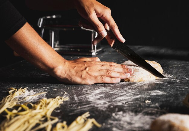 Close-up person cutting dough with knife 